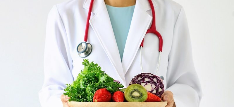 alimentation saine : un docteur tient une assiette de fruits et légumes frais