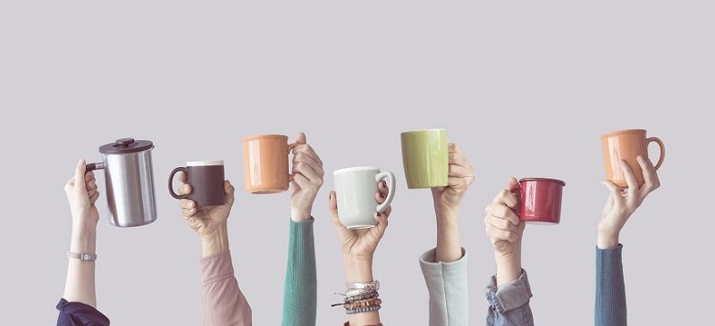 Plusieurs bras levés avec une tasse de café dans la main.