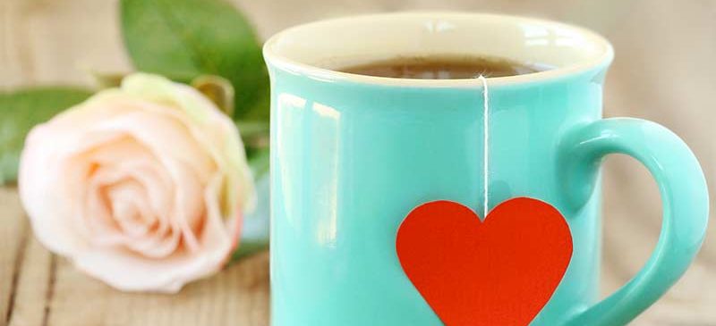 Une tasse avec un motif coeur contenant du thé vert