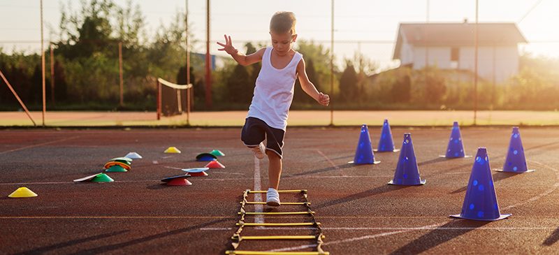 Petit garçon hyperactif sautant par-dessus des entraves dans un terrain d’entraînement