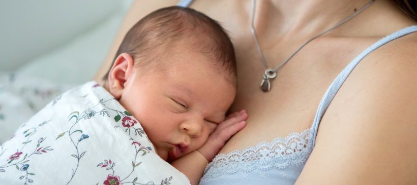 nourrisson en train de dormir dans les bras de sa maman