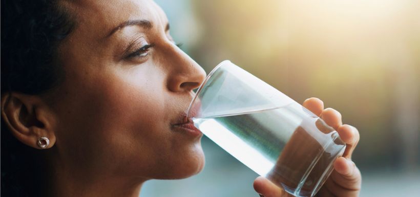 header de l'article "PFAS dans l'eau potable et cancers aux états-unis", femme qui boit un verre d'eau